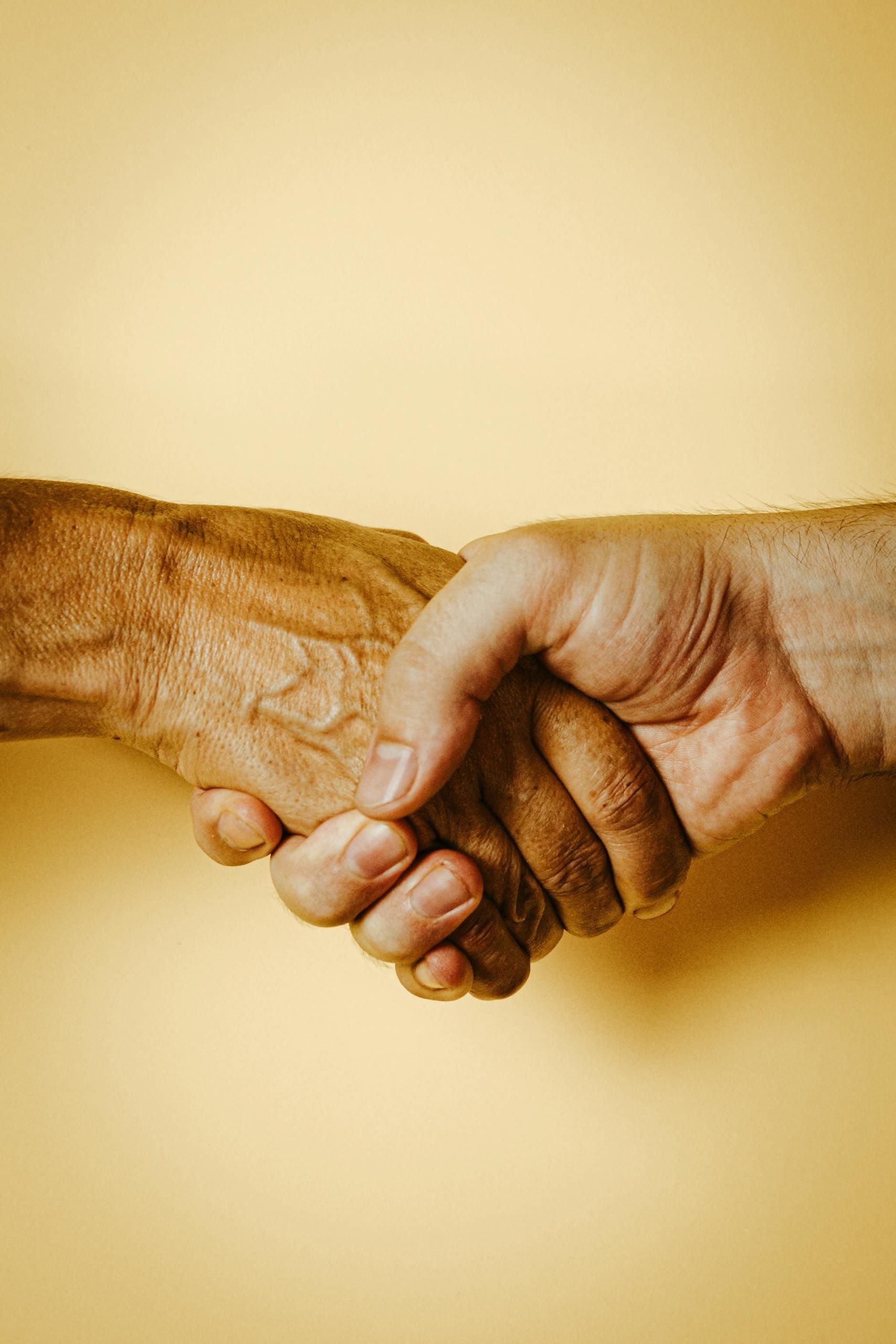 A close-up image of a handshake against a yellow background symbolizing unity and friendship.
